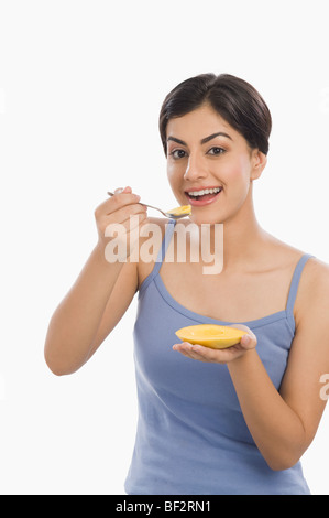 Donna di mangiare il mango con un cucchiaio Foto Stock