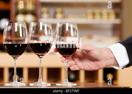 Mano d'uomo con in mano un bicchiere di vino in un bar Foto Stock