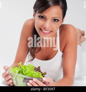 Donna che mantiene una ciotola di insalata di verdure e sorridente Foto Stock