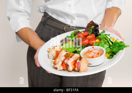 Metà vista in sezione di una donna tenendo un piatto di shish kebab Foto Stock