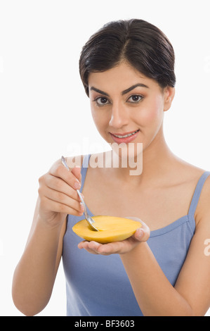 Ritratto di una donna di mangiare il mango con un cucchiaio Foto Stock