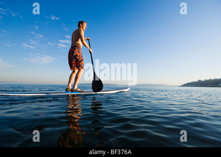 Un tardo 30's uomo caucasico su uno stand up paddle board sul Puget Sound nei pressi di Seattle, WA. Foto Stock