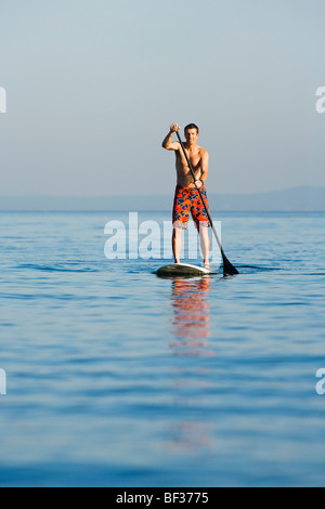 Un tardo 30's uomo caucasico su uno stand up paddle board sul Puget Sound nei pressi di Seattle, WA. Foto Stock