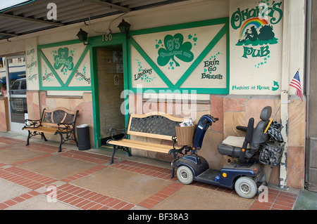 Una sedia a rotelle in stile scooter di mobilità è parcheggiata vicino all'entrata di un popolare Pub Irlandese nel vecchio quartiere towne di Orange, CA. Foto Stock