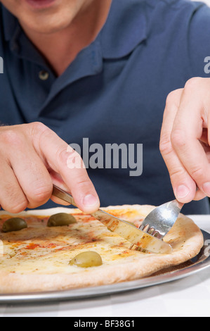 Uomo di mangiare la pizza con una forchetta e coltello Foto Stock