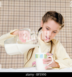 Close-up di una ragazza di versare il latte in una tazza Foto Stock