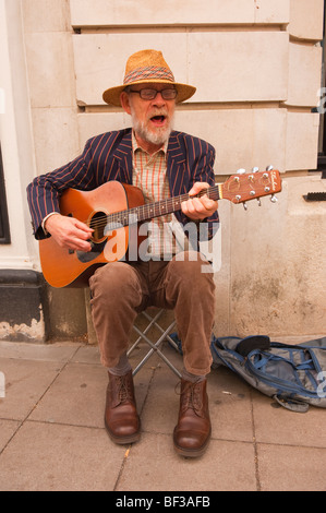 Un anziano uomo barbuto busker a suonare la chitarra musicista di strada a Norwich, Norfolk, Regno Unito Foto Stock