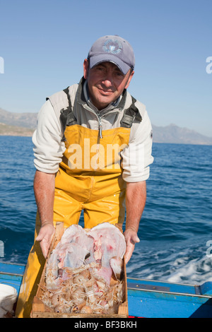 Pescatore sulla barca, presentando il pesce Foto Stock