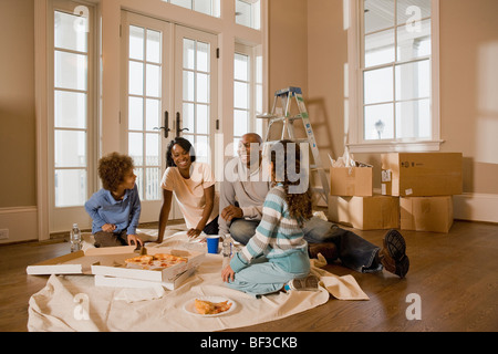 Famiglia mangiare sul pavimento nella nuova casa Foto Stock