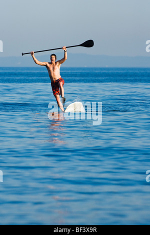 Una metà uomo adulto cadere in un stand up paddle board. Foto Stock