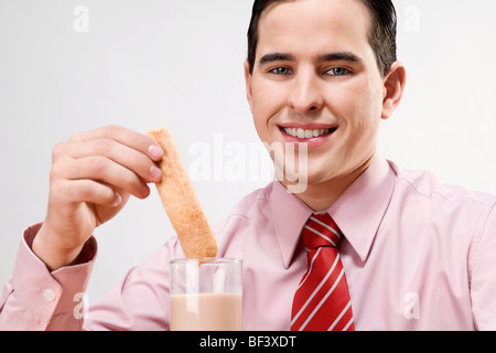 Ritratto di un imprenditore immergendo una fetta nel latte Foto Stock