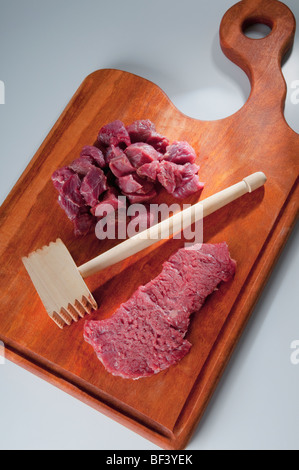 Close-up di carne a cubetti con un tenerizzatore Foto Stock