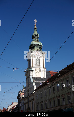 Torre di una chiesa nella città di Graz in Austria visto attraverso i cavi di alimentazione per la rete di tram Foto Stock