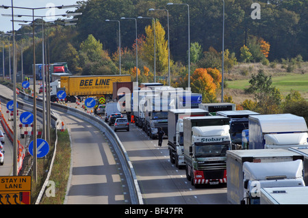 La polizia distanti girando intorno al camion paralizzata & altro traffico su autostrada M25, lavori stradali sezione dopo la chiusura a causa di un incidente Foto Stock