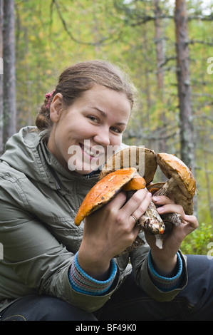 Donna russa tenendo i funghi in mani e sorridente nella fotocamera Foto Stock