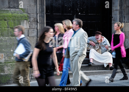 Il vecchio uomo barba abito vestito hare Krishna musicista di strada busk argento chitarra acciaio Edinburgh Fringe Festival gente camminare da blur Foto Stock