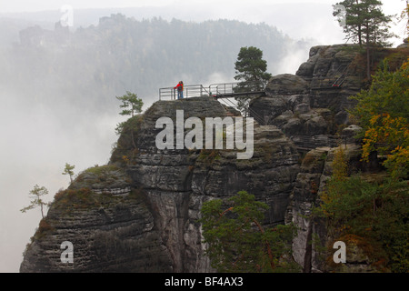 Bastei, formazioni rocciose con persone in piedi su una piattaforma di osservazione nella nebbia mattutina, Elba montagne di arenaria in autunno, Saxo Foto Stock
