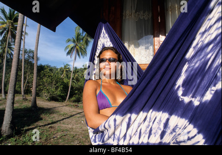 Giovane donna in una amaca sotto le palme di fronte una capanna nella baia di Tong Nai Pan, Koh Pha Ngan Isola, Thailandia, Asia Foto Stock