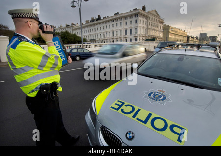 Un funzionario di polizia utilizzando un palmare fotocamera laser su una strada della città per la cattura di velocizzare gli automobilisti Foto Stock