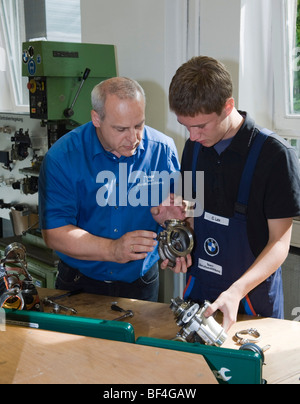 Maestro di spiegare ad un apprendista mentre si lavora su una parte di un motore in BMW training center for automotive meccatronica, M Foto Stock