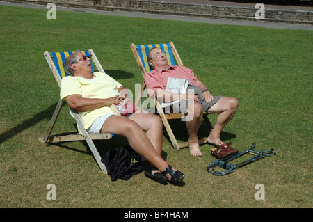 Di mezza età matura a prendere il sole in sedie a sdraio, Giardini inferiori di Bournemouth Dorset, England, Regno Unito Foto Stock