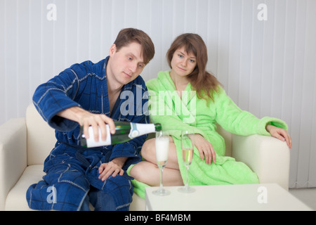 L'uomo versa alla donna in un bicchiere di spumante Foto Stock