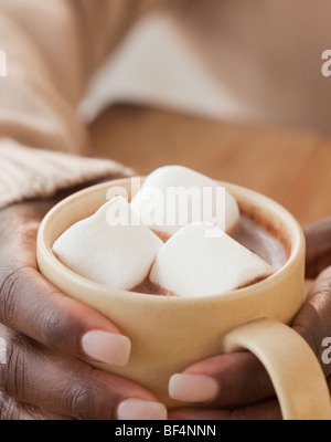 Donna africana holding tazza di cioccolata calda e marshmallows Foto Stock