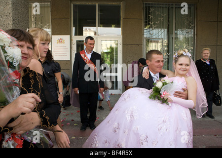 Lo sposo che trasportano sposa presso la reception, Ekaterinburg, Uralmash, Russia Foto Stock