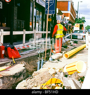 Un lavoratore in piedi da una trincea di lavoro sulla nuova sostituzione Vittoriano Thames Water Costruzioni di pipeline in centro a Londra England Regno Unito KATHY DEWITT Foto Stock