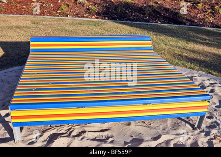 Una panchina nel parco con muti stecche colorate Foto Stock