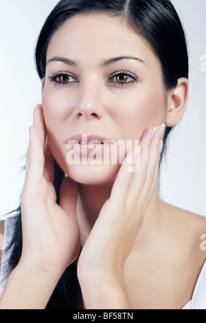 Giovani dai capelli scuri di accarezzare la donna con entrambe le mani su di lei le guance, di bellezza Foto Stock