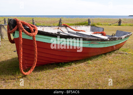Vecchia barca di legno con una corda rossa sulle rive del fiume San Lorenzo in Quebec. Foto Stock