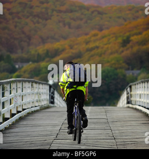 Un ciclista che attraversa il vecchio di legno di proprietà privata ponte a pedaggio a Penmaenpool, Mawddach estuario del fiume, Snowdonia National Park Regno Unito Foto Stock