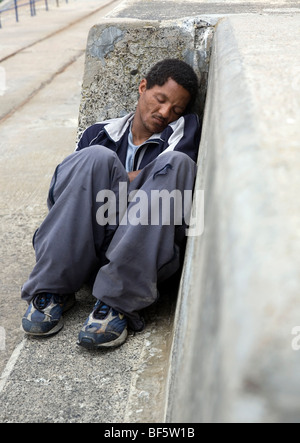 Uomo dorme sul banco di cemento Foto Stock