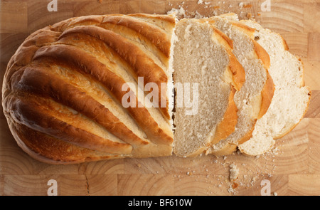 Bianco fresco bloomer crostini di pane tagliato a fette irregolare su un blocco di legno Foto Stock