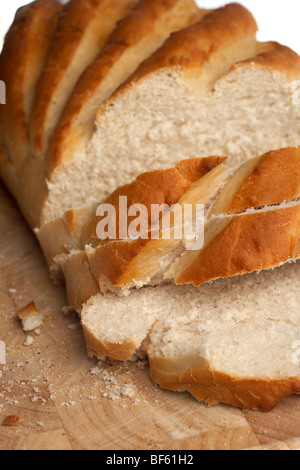 Bianco fresco bloomer crostini di pane tagliato a fette irregolare su un blocco di legno Foto Stock