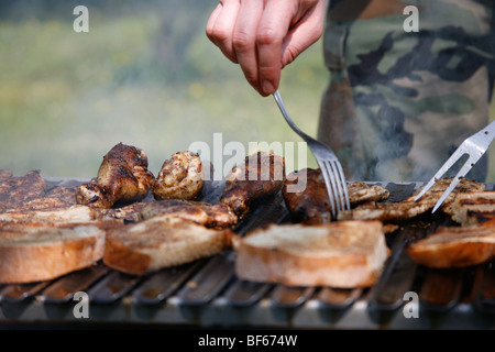 L'uomo la preparazione di carne alla griglia su un barbecue in estate in giardino Foto Stock