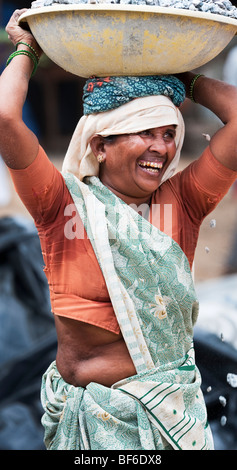 Donna indiana che lavora sulle strade, trasportando pietre in una ciotola sul suo capo. Puttaparthi, Andhra Pradesh, India Foto Stock