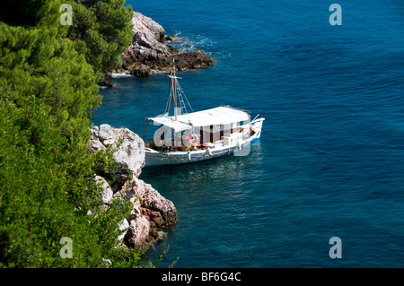 Una tradizionale barca greca o caicco legato ormeggiata su la costa rocciosa sull'isola greca di Skopelos, Le Sporadi, isole greche, Grecia Foto Stock