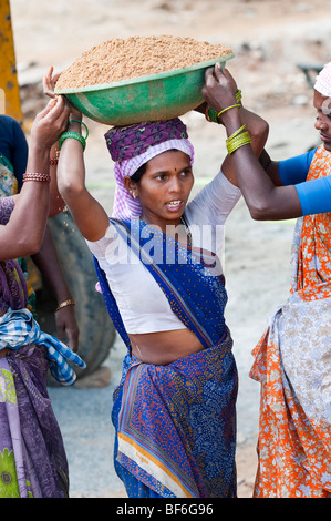 Donna indiana che lavora sulle strade, sollevamento e trasporto di sabbia in una ciotola sul suo capo. Puttaparthi, Andhra Pradesh, India Foto Stock