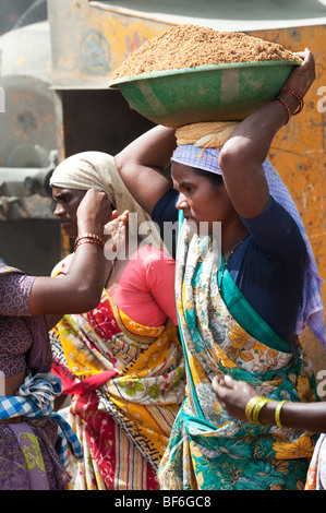 Donna indiana che lavora sulle strade, sollevamento e trasporto di sabbia in una ciotola sul suo capo. Puttaparthi, Andhra Pradesh, India Foto Stock