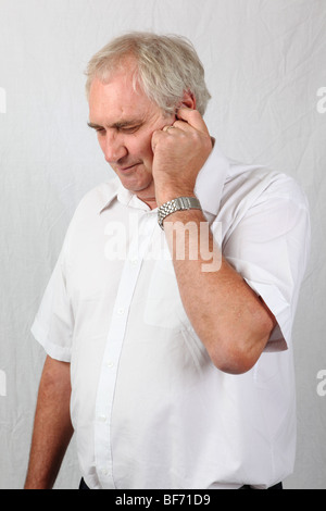 50s 60s maschio maturo con il dito in ear sofferenza da orecchio ache infezione dolore acufeni perdita di udito orecchio interno problema di bilanciamento Foto Stock