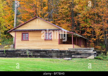 Una rustica casa in legno siede tra il fogliame di autunno in Vermont, USA. Foto Stock