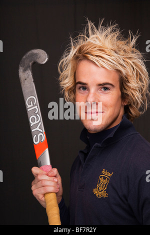 Regno Unito, Gran Bretagna. Testa e spalle ritratto di un sorridente giovane uomo che indossa una maglietta di hockey e tenendo un bastone Foto Stock