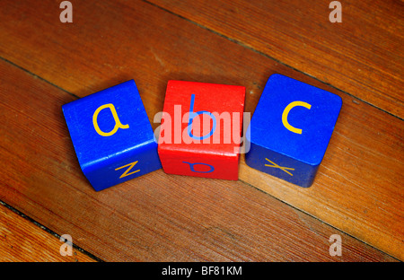 Tre bambini di blocchi di legno con a b c scritto su di loro, su un pavimento di legno in un vivaio per insegnare l'ortografia lettura scrittura Foto Stock