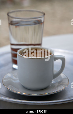 Il caffè turco noto come caffè cipriota nella repubblica di cipro europa servito con un bicchiere di acqua per uso potabile in seguito Foto Stock