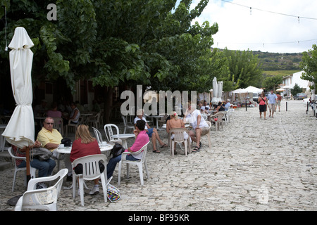 I turisti in street cafe in lastricato in pietra piazza villaggio omodos troodos vino regione Repubblica di Cipro in Europa Foto Stock