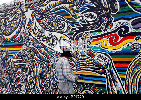 Un artista dipinge il muro di Berlino, all'East Side Gallery, a 1.3km-lungo la sezione della parete vicino al centro di Berlino. Foto Stock