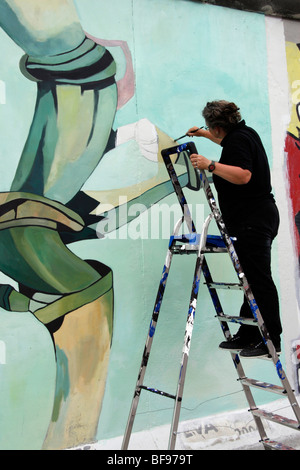 Un artista dipinge il muro di Berlino, all'East Side Gallery, a 1.3km-lungo la sezione della parete vicino al centro di Berlino. Foto Stock