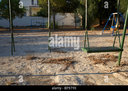 Rotto abbandonato childs altalena nel parco giochi Foto Stock